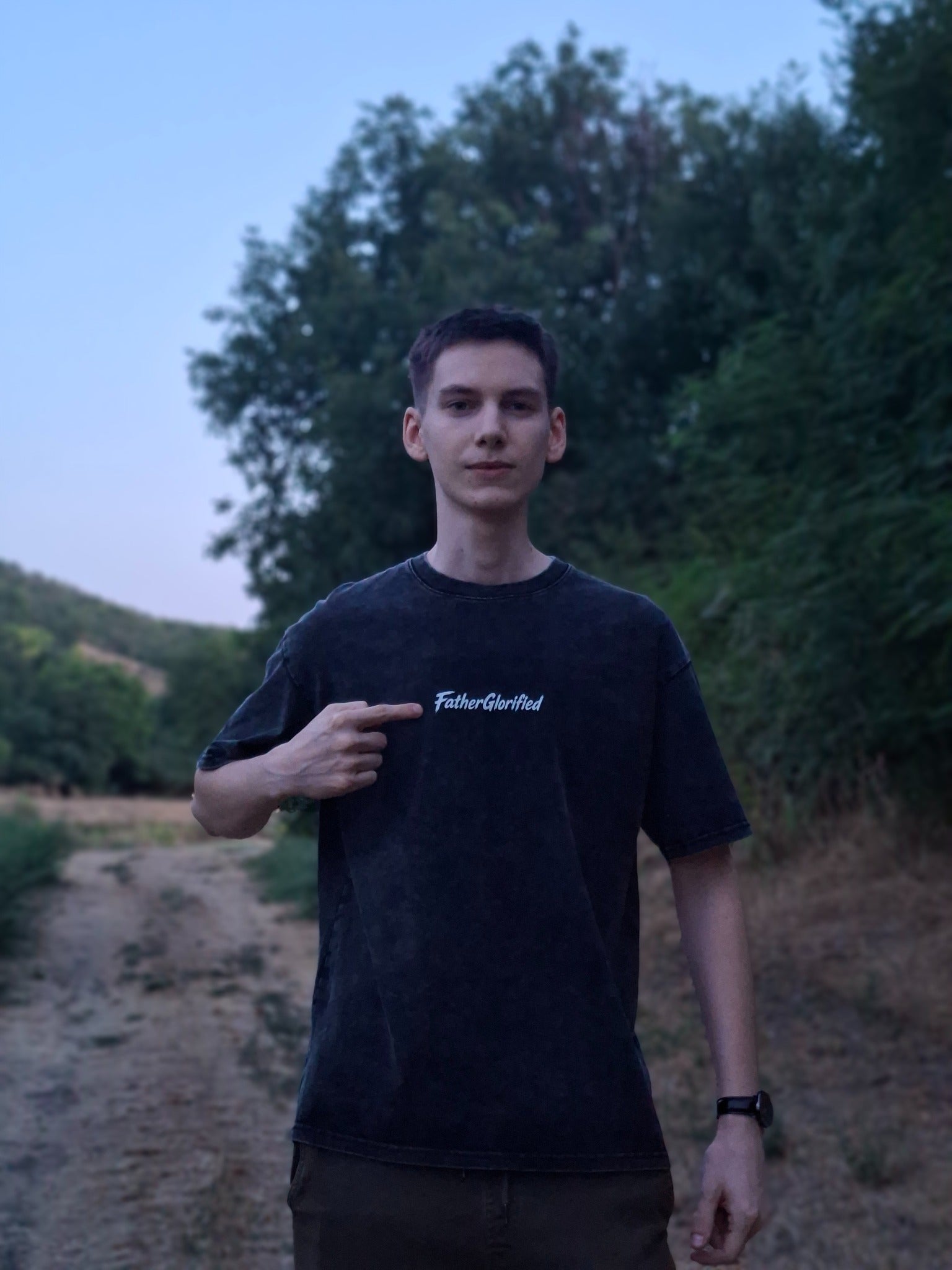 FatherGlorified tee worn outdoors, pointing to the chest logo
